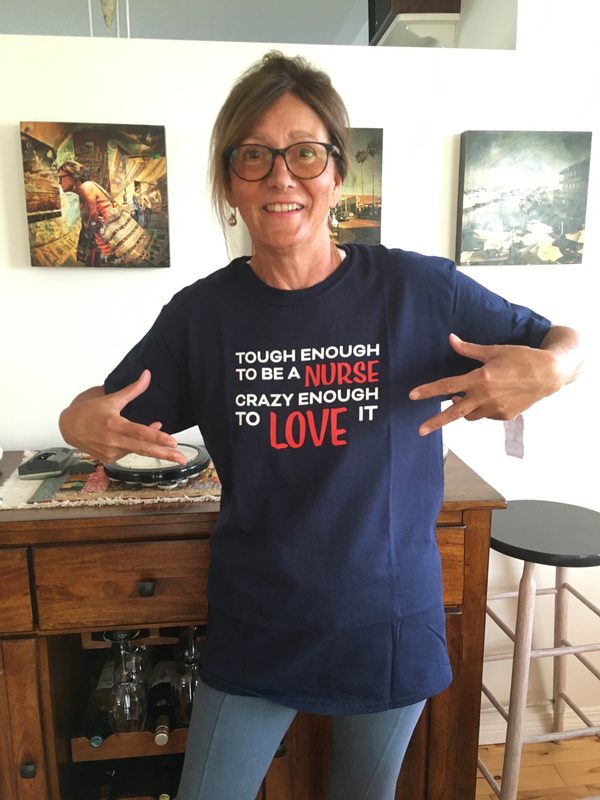 Paula pointing both hands at her t-shirt, which reads: tough enough to be a nurse, crazy enough to love it.